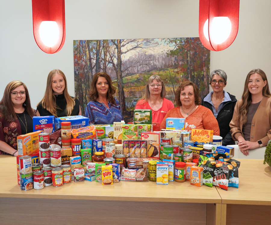 A Group Of Ladies Around The Canned Food Drive